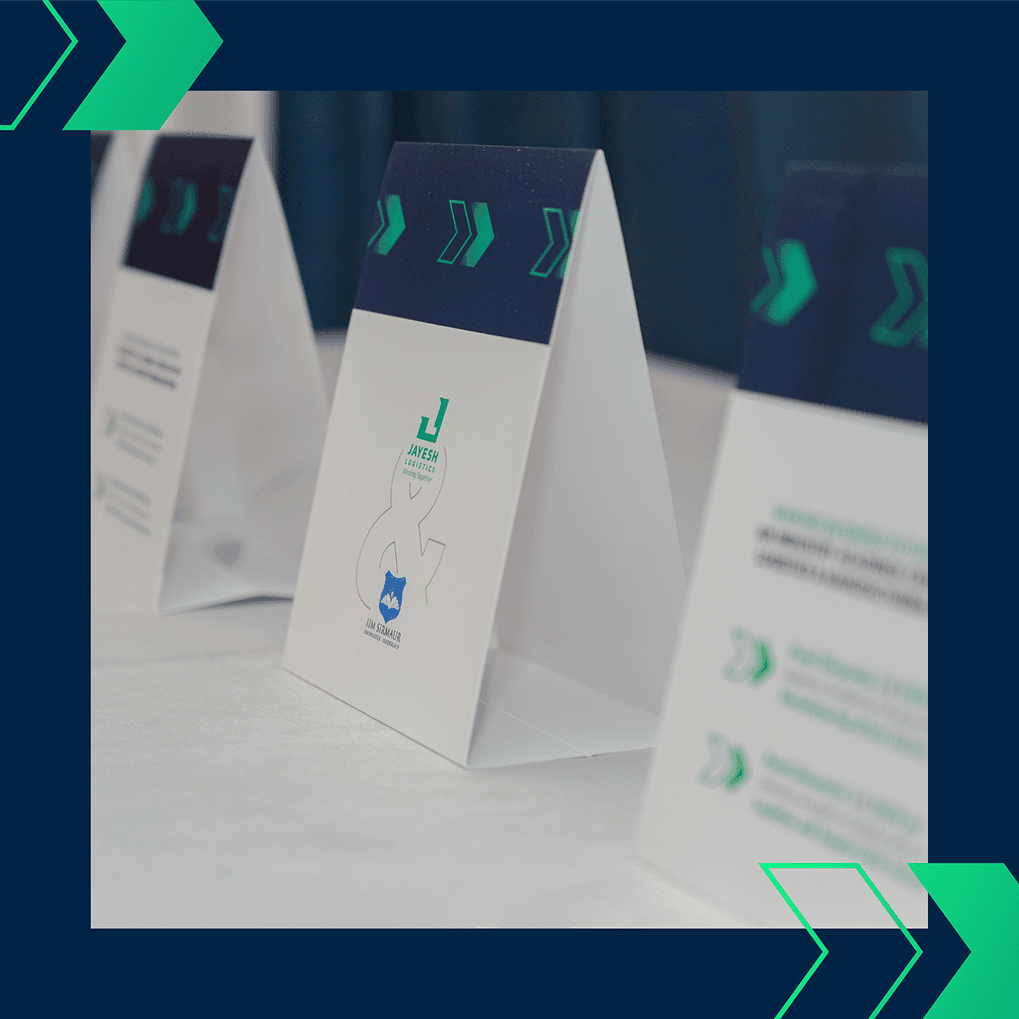 Close-up of branded table display signs featuring Jayesh Logistics and IIM Sirmaur logos at the Conclave on November 18, 2024.